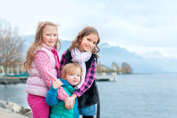 Fototapeta na wymiar Outdoor portrait of 3 cute little girls, wearing warm coats
