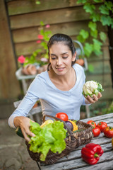 Woman with fresh vegetables in a basket at the garden table