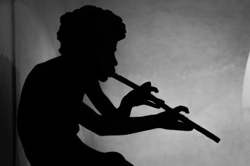 A silhouette of a boy or god Pan playing a flute