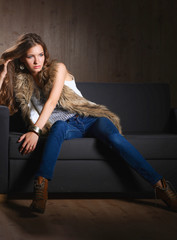 Portrait of elegant woman sitting on black sofa wearing a blue