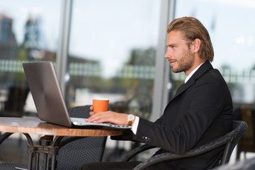 Businessman using his laptop computer in a coffee shop