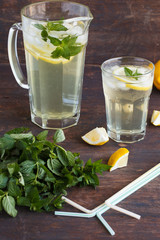Lemonade with fresh lemon and mint on wooden background
