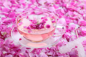 Tea with rose petals in a glass Cup with sugar crystals on the shelf. Rose water.