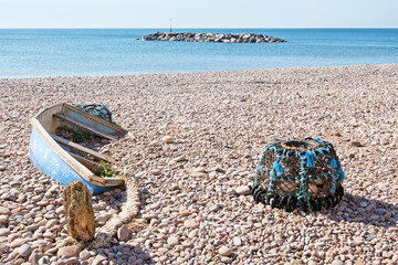Fototapeta na wymiar Fishing no more. old small boat and lobster pot,abandoned on beach.