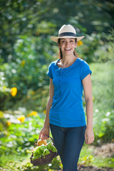 At garden, beautiful woman holding a vegetables basket