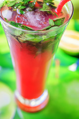 Refreshing summer drink with berry in glass on a green background with the cut lime.