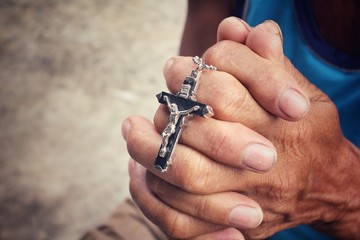 Senior man hands praying with cross