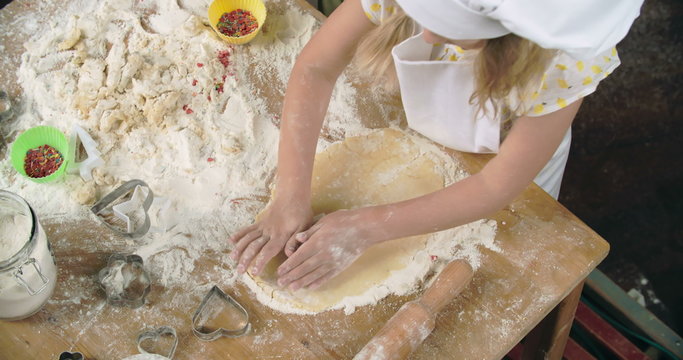 High angle view of little girls rolling out dough and cutting out cookies 