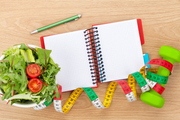 Dumbells, tape measure, healthy food and notepad for copy space.