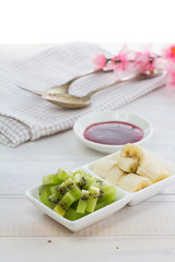 Raspberry jam with kiwi and banana over wooden vintage background