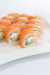 Salmon (philadelphia) sushi roll on a white plate with ginger and wasabi