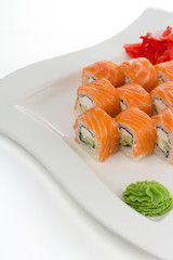 Salmon (philadelphia) sushi roll on a white plate with ginger and wasabi