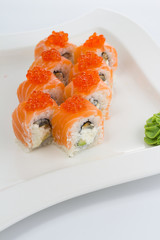 Salmon (philadelphia) sushi roll on a white plate with ginger and wasabi