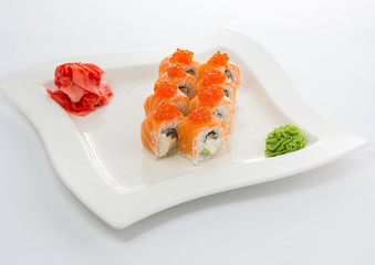 Salmon (philadelphia) sushi roll on a white plate with ginger and wasabi