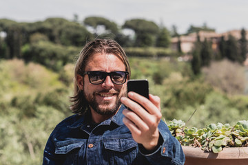 Casual man with long blonde hair and beard making selfie outdoor