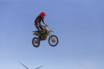 A motorcycle rider high up in the air and small parts of a turbine is visible