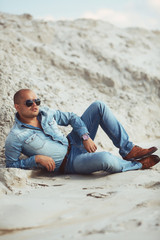 young guy in jeans clothes lying on the sand in Egypt