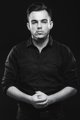 Handsome man with beard, posing in black shirt in studio