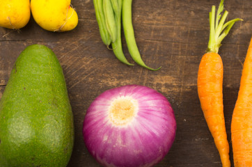 all-natural avocado, onion and carrots on wooden board