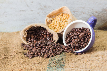 coffee cup and coffee beans on burlap textile and brown background.