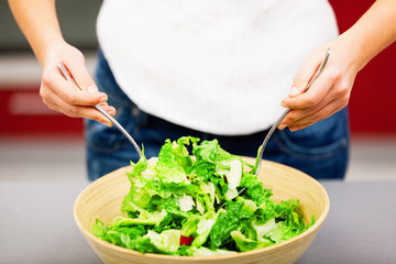 Young woman making salad