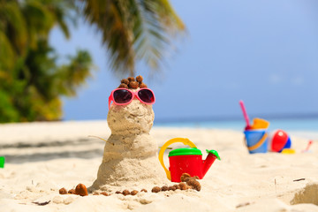 Sandy snowman and toys at sand beach