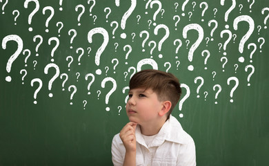 Little boy thinking surrounded question marks