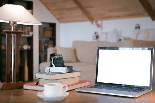 Stack of old books, open laptop and old camera over wooden table, retro filtered image