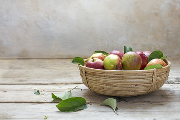 Organic apples in a small basket on an rustic wooden table