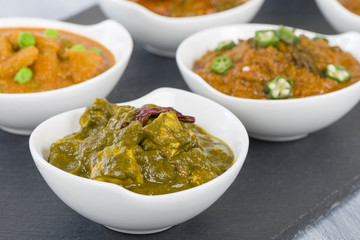 Palak Paneer - Cottage cheese cooked in a pureed spinach curry sauce. Other vegetarian curries on background.