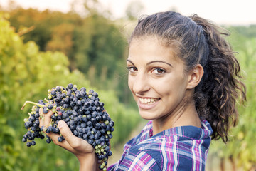 pretty girl shows grapes in a vineyard