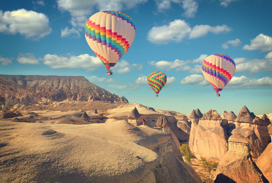 Vintage photo of hot air balloon flying over rock landscape at Cappadocia Turkey.