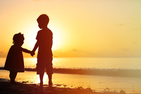 little boy and girl holding hands at sunset