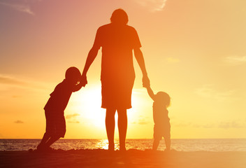 Fototapeta premium father and two kids walking at sunset