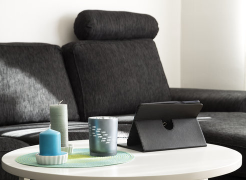 A table with candles and a tablet with a sofa in the background