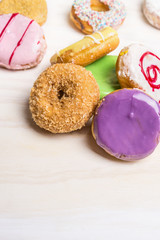 fresh colorful donuts on white wooden background, close up