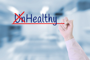 Doctor hand writing unHealthy ,Healthy with marker on on visual screen over green nature blurred background.