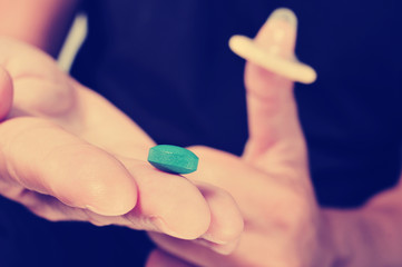 young man with blue pill and condom, filtered