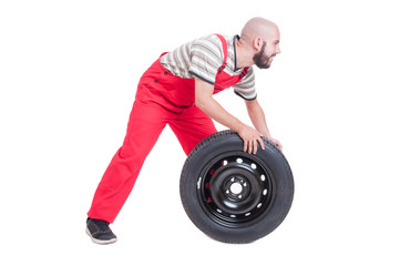 Happy mechanic pushing a  new car wheel