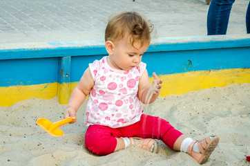 Little beautiful girl baby play in the sandbox and sand toys on the playground