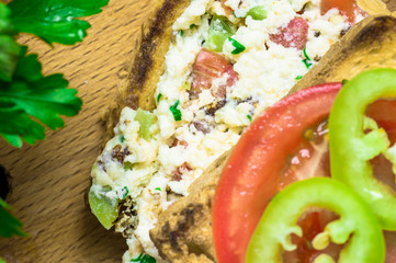 Sandwich with scrambled eggs, tomato and pepper closeup