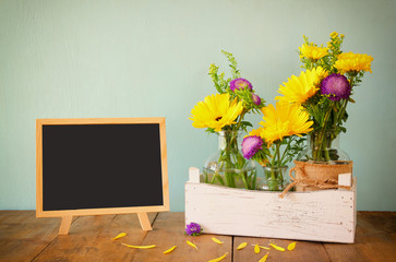 summer bouquet of flowers and wooden blackboard on the wooden table
