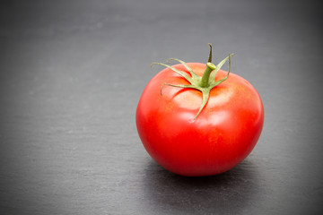 rote Tomate auf Schieferplatte mit Vignette