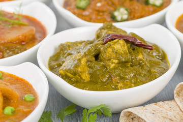 Palak Paneer - Cottage cheese cooked in a pureed spinach curry sauce. Other vegetarian curries on background.