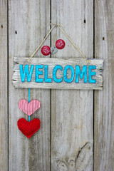 Welcome sign with hearts and bottle caps hanging on rustic wood door