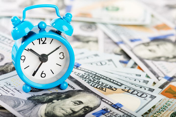 Time is money. Alarm clock and dollar banknotes.