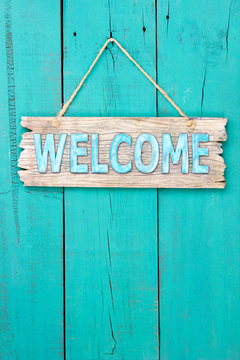 Welcome sign hanging on antique teal blue rustic door