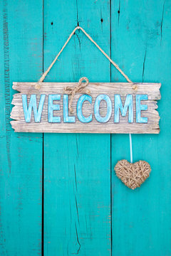 Welcome sign with heart hanging on teal blue door