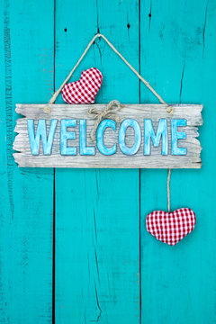 Welcome sign with hearts hanging on teal blue door
