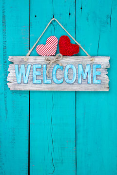 Welcome sign with hearts hanging on teal blue door